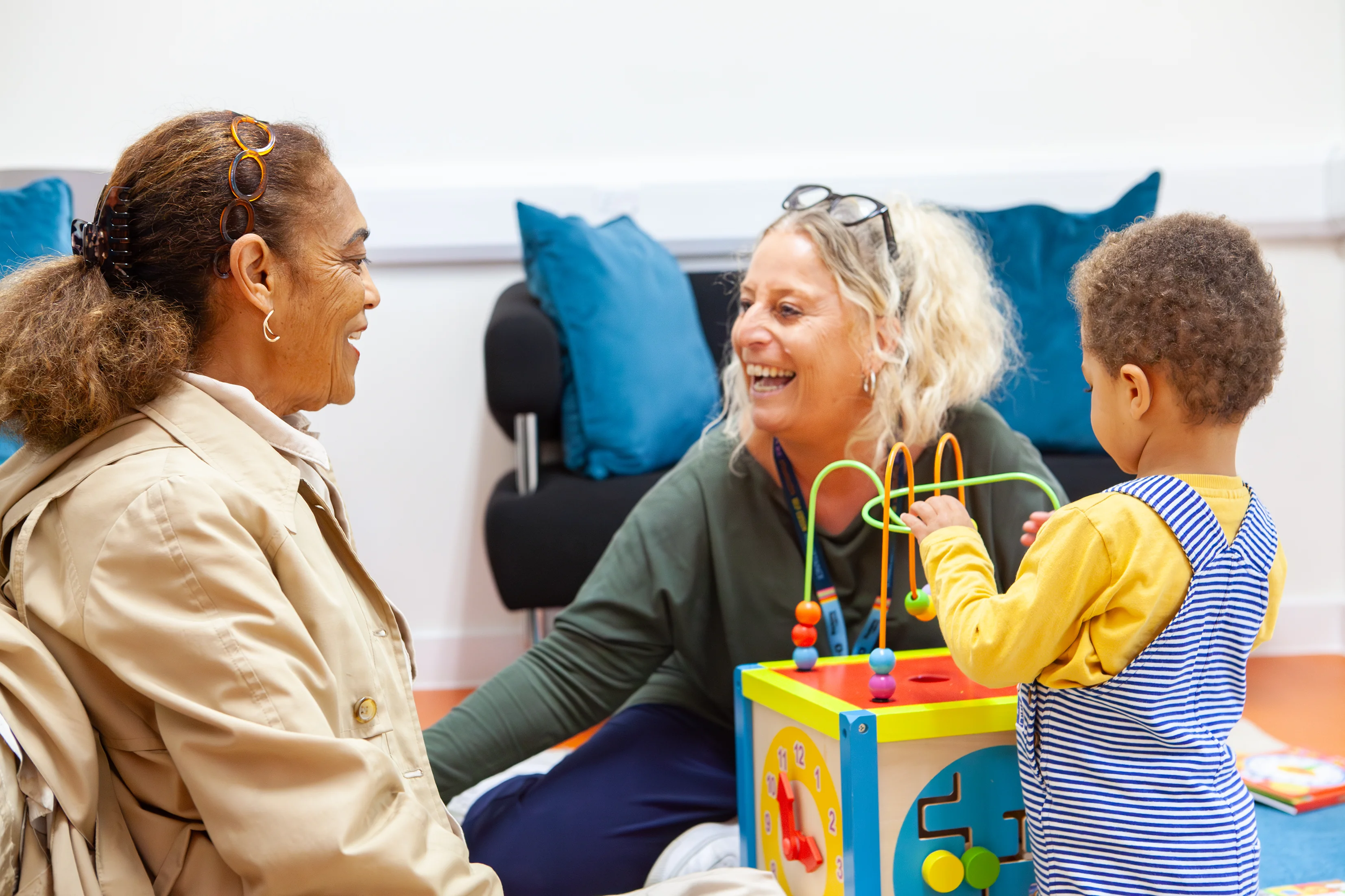 A parent or carer watching while a young child plays with a toy.