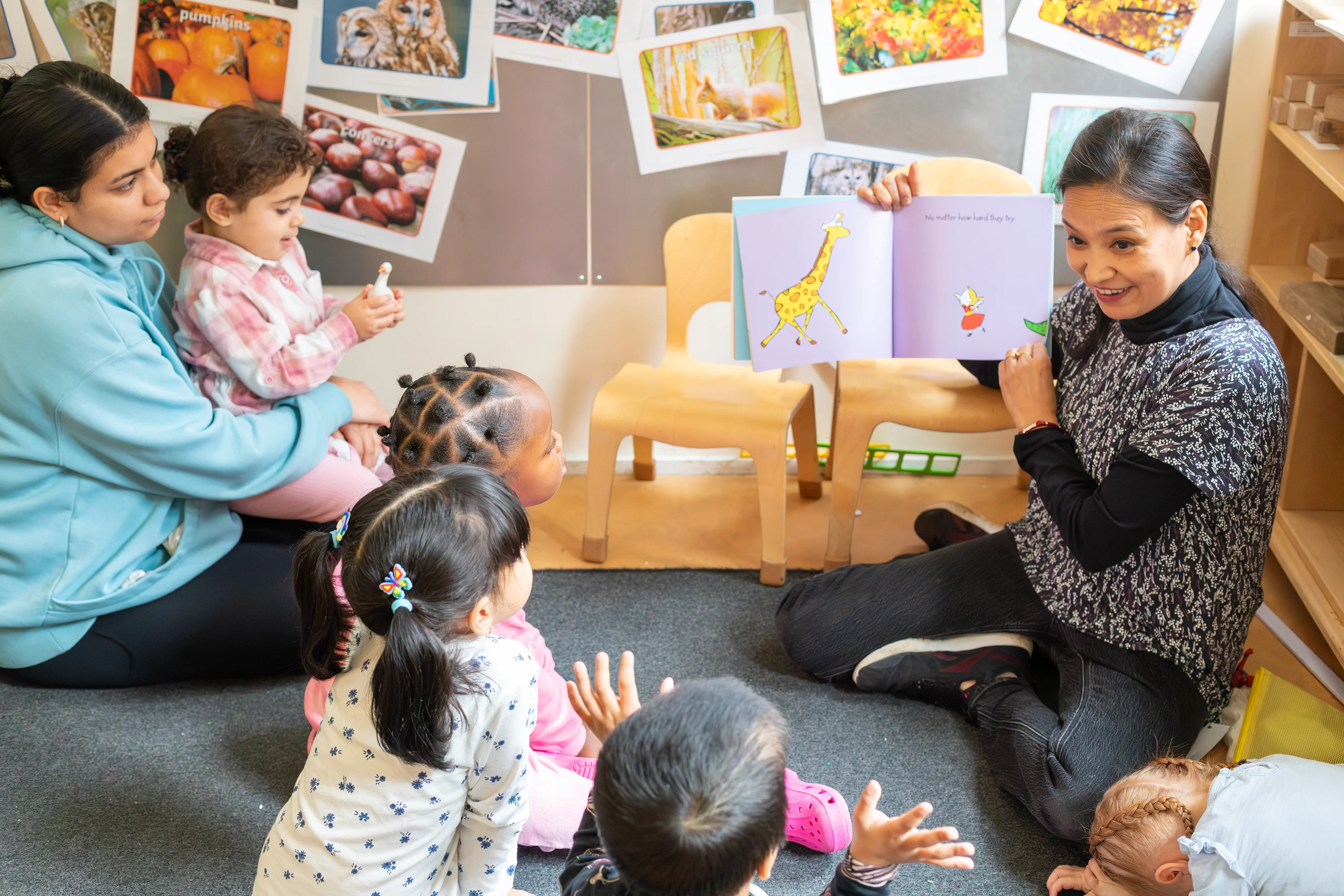Woman reading a book to young children at 1a Family Hub