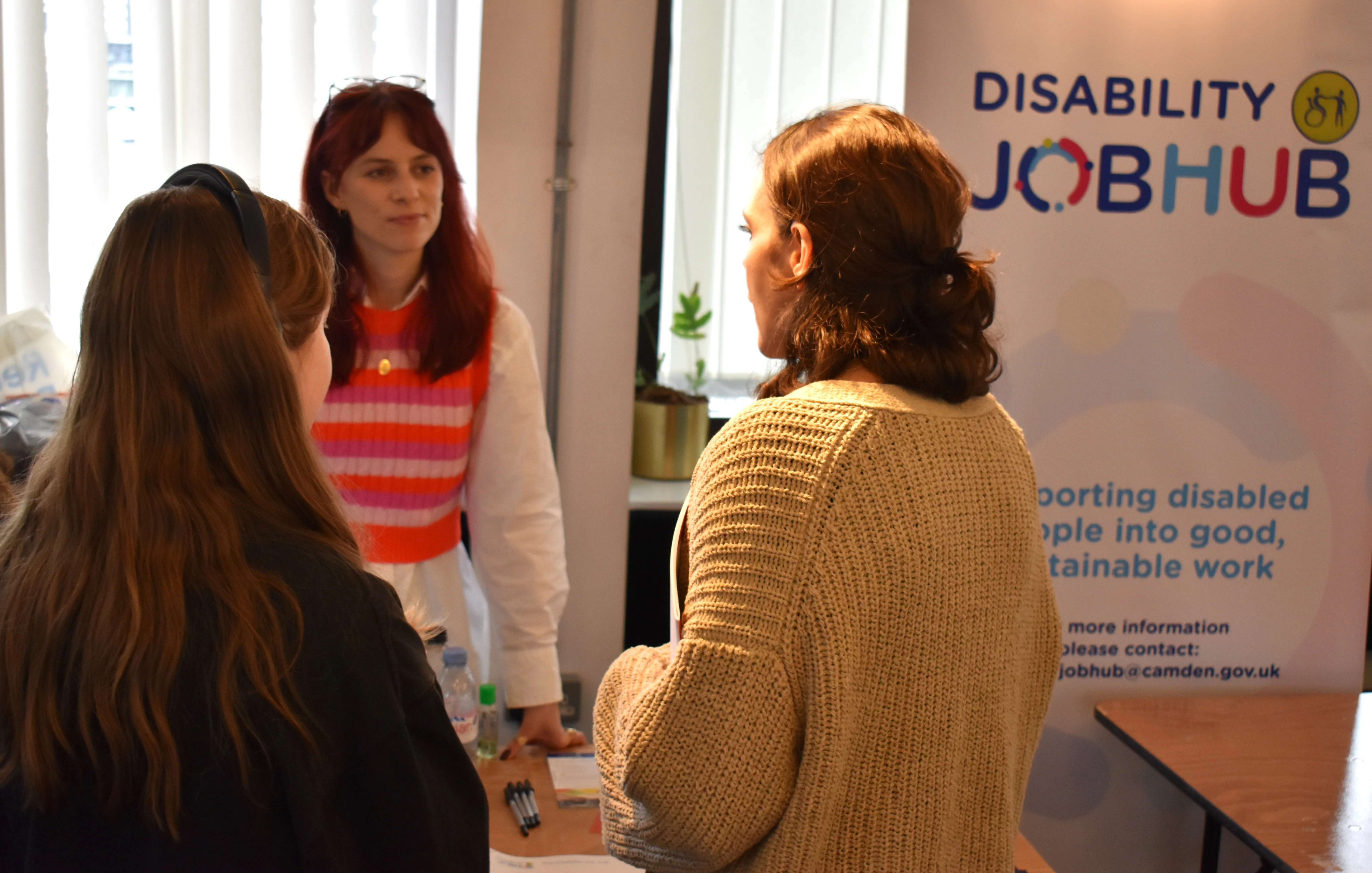 Two adults and a young person talking to each other at a Disability Job Hub.